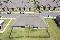 Aerial view of a modern apartment community showcasing beautiful green spaces and ample parking, perfect for urban living.
