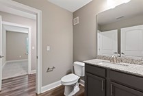 Modern bathroom with elegant granite countertop, sleek fixtures, and a view into a cozy, carpeted bedroom.