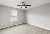 Bright, spacious room with plush carpet, sleek ceiling fan, and elegant window blinds perfect for modern living.