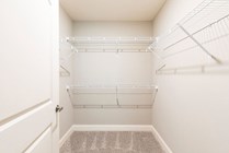 Bright walk-in closet with modern wire shelving and plush carpet, perfect for organized storage in a stylish living space.