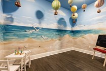 Charming kids center with a vibrant beach mural featuring seagulls and dunes, conveniently attached to the fitness center