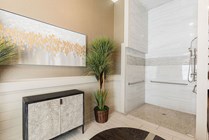 Elegant bathroom featuring modern walk-in shower, stylish artwork, and lush green plant for a touch of nature.