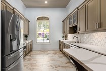Luxurious modern kitchen with sleek stainless steel appliances, elegant marble flooring, and custom cabinetry, boasting abundant natural light.