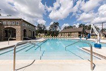 Inviting swimming pool with crystal-clear water, surrounded by stone buildings and lush greenery under a bright blue sky, perfect for relaxation and leisure.